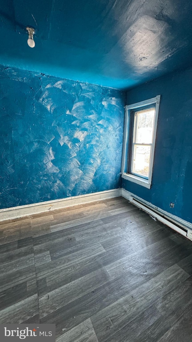 unfurnished room featuring dark hardwood / wood-style flooring and a baseboard heating unit