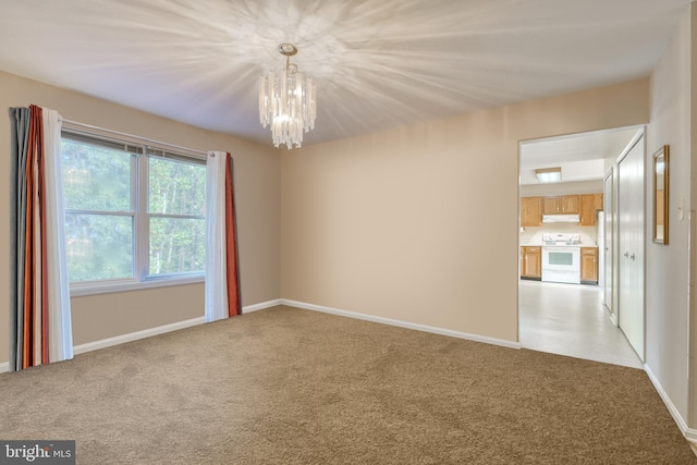 carpeted spare room featuring an inviting chandelier