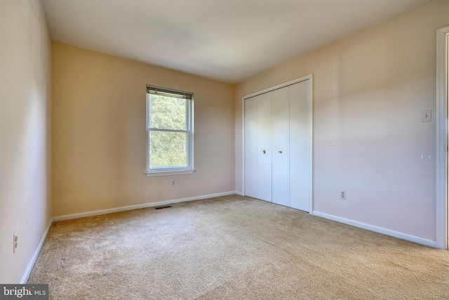 unfurnished bedroom with light colored carpet and a closet