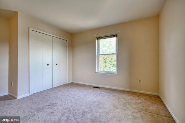 unfurnished bedroom with a closet and light colored carpet