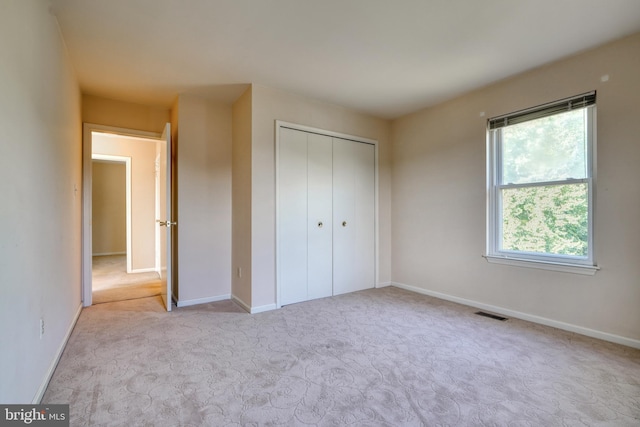 unfurnished bedroom with light colored carpet, a closet, and multiple windows