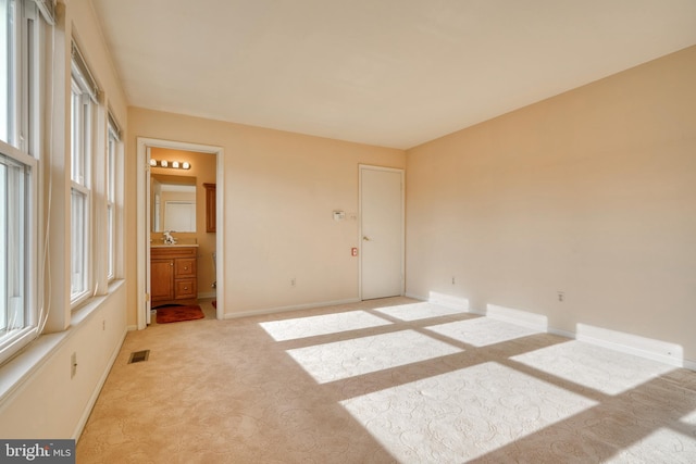 unfurnished room featuring light colored carpet and sink