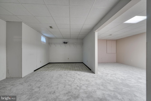 basement featuring light colored carpet and a paneled ceiling