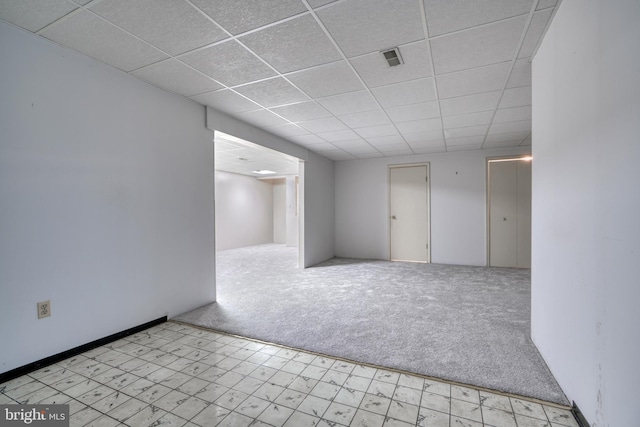 carpeted spare room with a drop ceiling