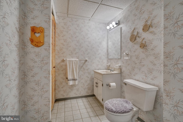 bathroom featuring a paneled ceiling, toilet, tile floors, and vanity