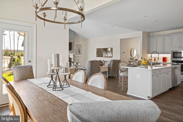 dining space with vaulted ceiling, sink, dark wood-type flooring, and a chandelier