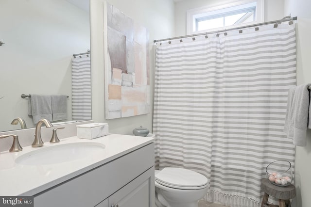 bathroom with toilet and vanity with extensive cabinet space