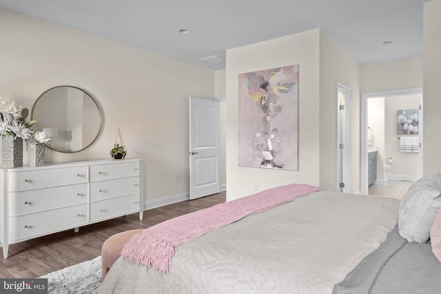 bedroom featuring connected bathroom and dark hardwood / wood-style floors