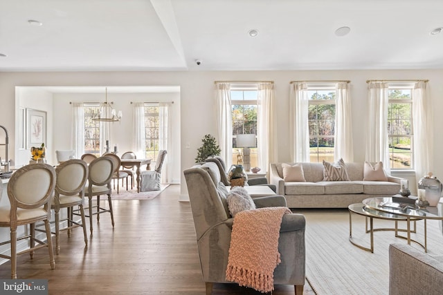 living room featuring an inviting chandelier, light hardwood / wood-style flooring, and a wealth of natural light