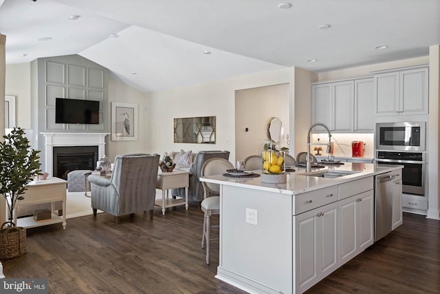 kitchen featuring dark hardwood / wood-style floors, stainless steel appliances, a kitchen island with sink, sink, and a kitchen breakfast bar