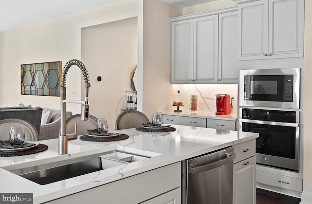 kitchen featuring white cabinetry, sink, stainless steel appliances, and light stone countertops