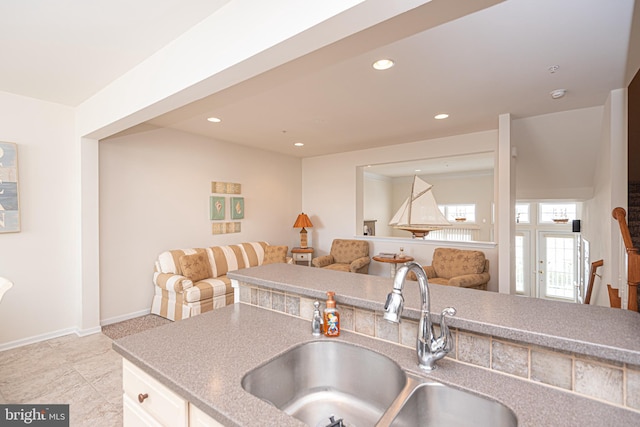 kitchen featuring white cabinetry, sink, and light tile flooring