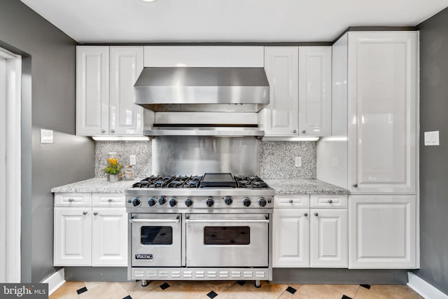 kitchen featuring backsplash, double oven range, wall chimney range hood, and white cabinets