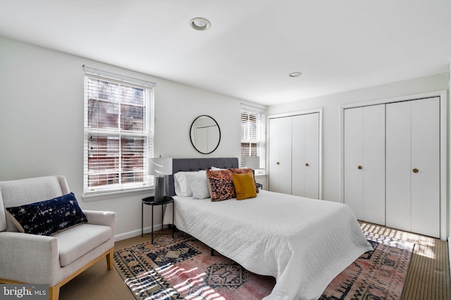 bedroom with multiple closets and dark wood-type flooring