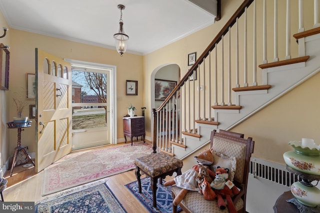 foyer with ornamental molding and light hardwood / wood-style floors