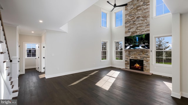 living room with crown molding, a fireplace, dark hardwood / wood-style floors, and plenty of natural light