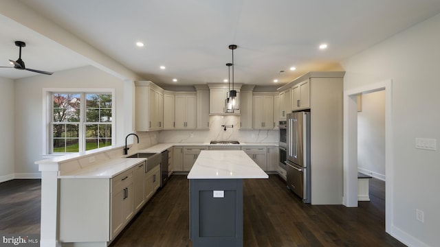 kitchen featuring hanging light fixtures, a center island, light stone countertops, vaulted ceiling, and dark hardwood / wood-style flooring