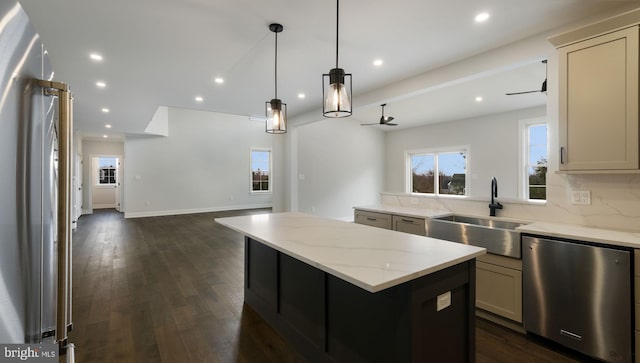 kitchen featuring dark wood-type flooring, light stone counters, a center island, stainless steel dishwasher, and sink