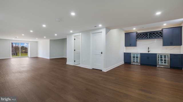 bar with dark hardwood / wood-style floors, blue cabinetry, wine cooler, and tasteful backsplash