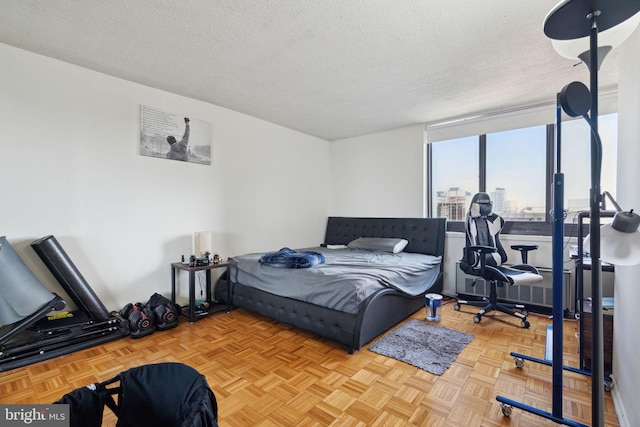 bedroom featuring light parquet floors, radiator, and a textured ceiling