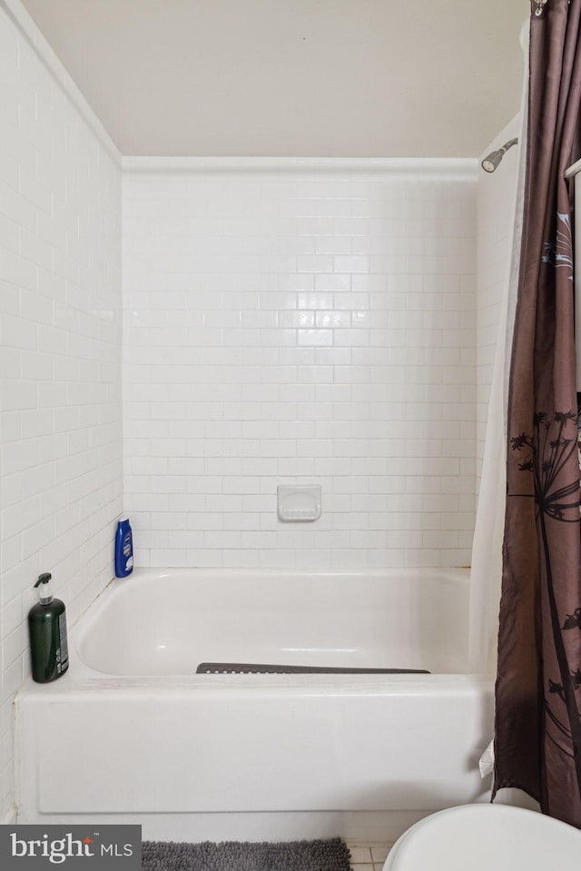 bathroom featuring shower / tub combo, tile flooring, and toilet