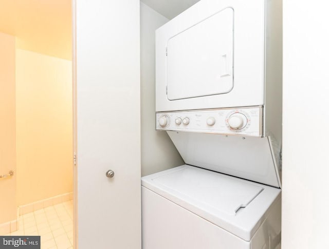 washroom with light tile floors and stacked washer and dryer