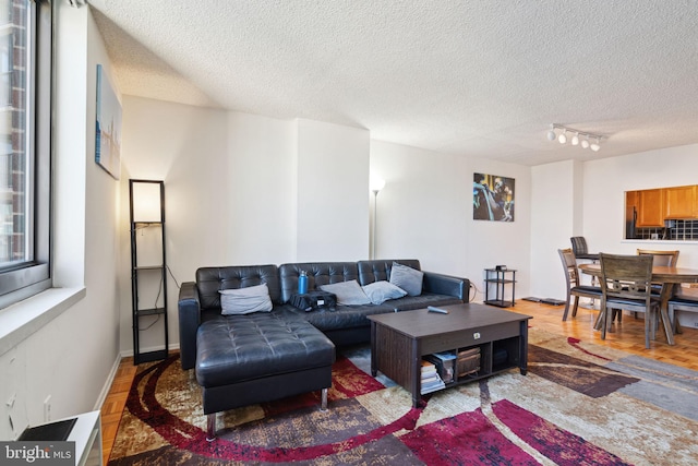 living room featuring parquet flooring, rail lighting, and a textured ceiling