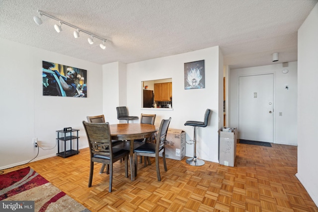 dining room with light parquet flooring, rail lighting, and a textured ceiling