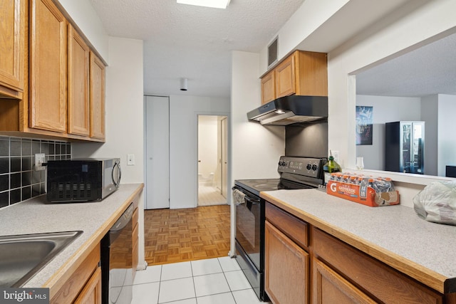 kitchen featuring sink, backsplash, black appliances, light parquet flooring, and a textured ceiling