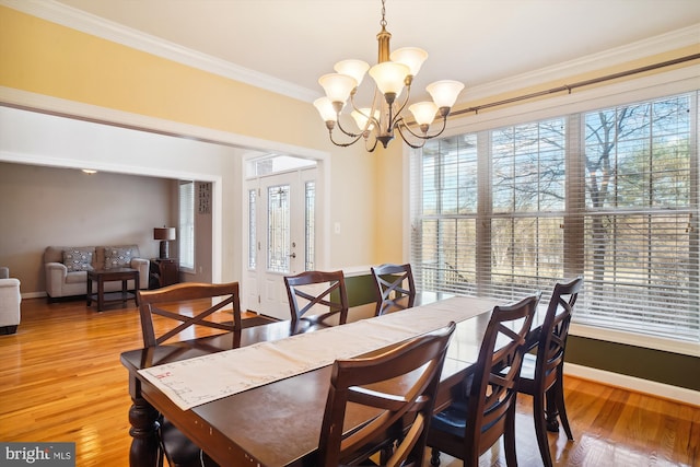 dining area with a chandelier, crown molding, and light wood-type flooring