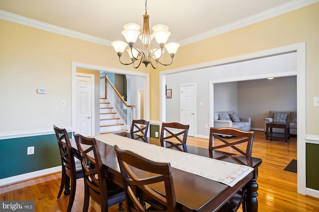 dining room featuring a notable chandelier, light wood-type flooring, and crown molding