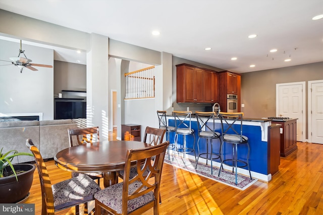 dining room with sink, ceiling fan, and light wood-type flooring