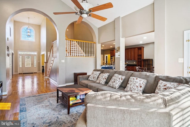 living room featuring high vaulted ceiling, ceiling fan, and light wood-type flooring