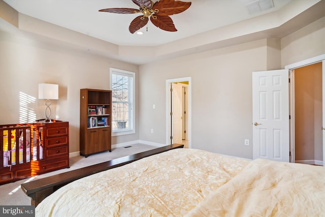 carpeted bedroom featuring a tray ceiling and ceiling fan