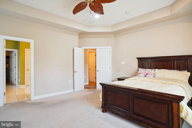 carpeted bedroom with ceiling fan and a raised ceiling