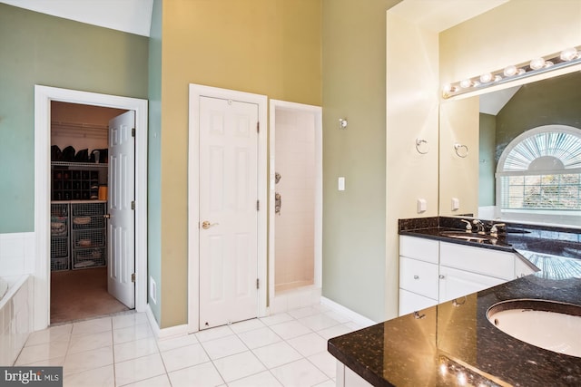 bathroom with tiled bath, large vanity, tile floors, and double sink