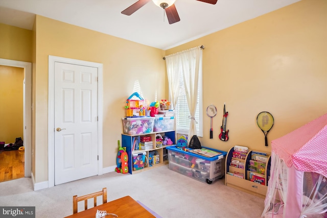 recreation room with ceiling fan and light carpet