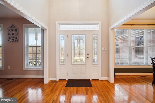 foyer entrance featuring ornamental molding, a healthy amount of sunlight, and light hardwood / wood-style flooring