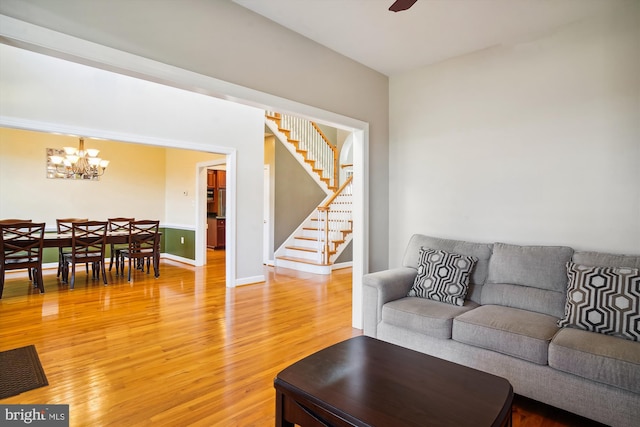 living room with ceiling fan with notable chandelier and light hardwood / wood-style flooring