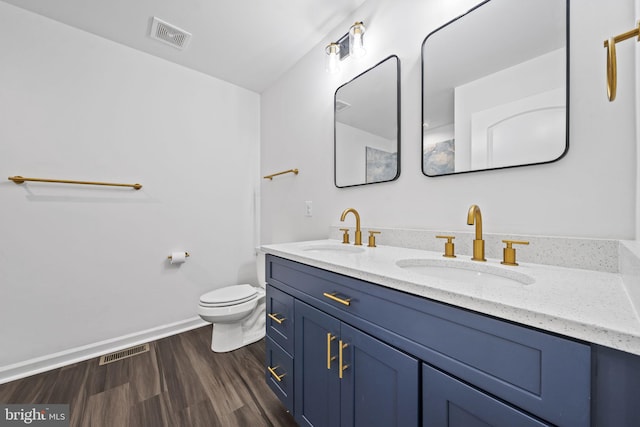 bathroom with double sink vanity, toilet, and hardwood / wood-style floors