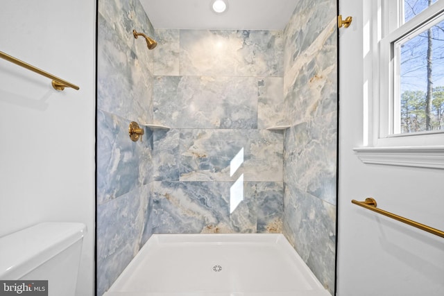 bathroom with a tile shower and toilet