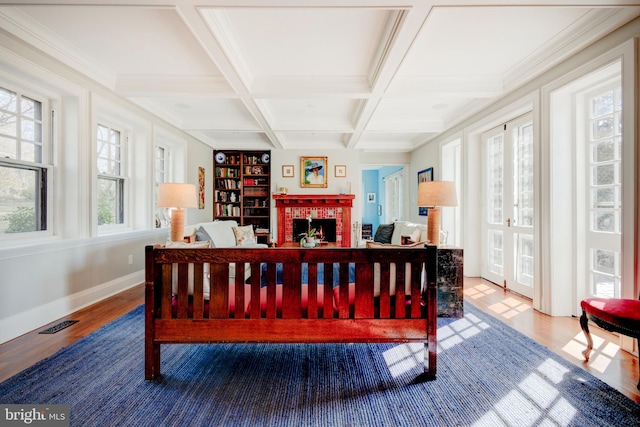 bedroom with hardwood / wood-style floors, beam ceiling, coffered ceiling, and a brick fireplace