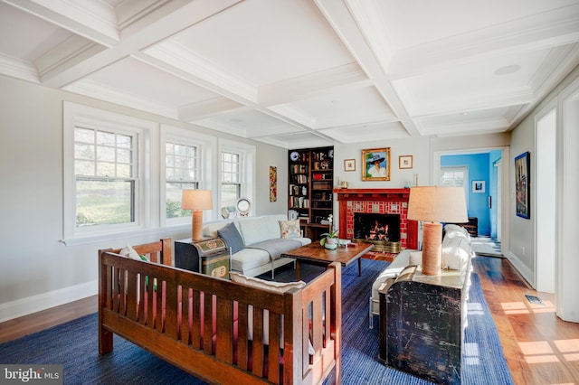 living room featuring coffered ceiling, dark wood-type flooring, a fireplace, beam ceiling, and crown molding