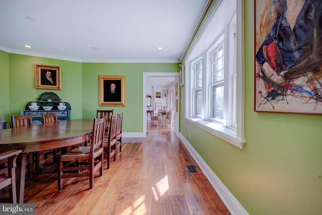 dining area with crown molding and light wood-type flooring