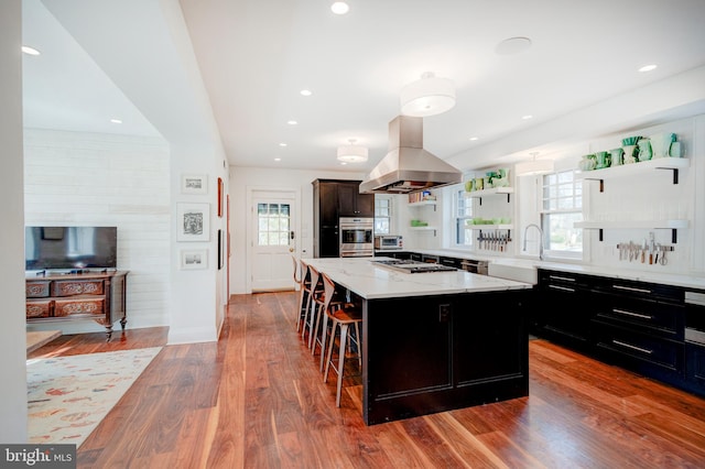 kitchen with hardwood / wood-style floors, a kitchen bar, island exhaust hood, and a center island