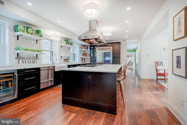 kitchen featuring a kitchen breakfast bar, a kitchen island, light wood-type flooring, and exhaust hood