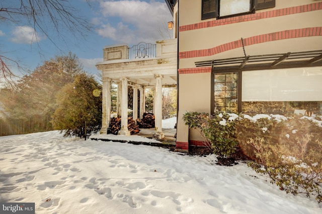 snow covered rear of property with a balcony