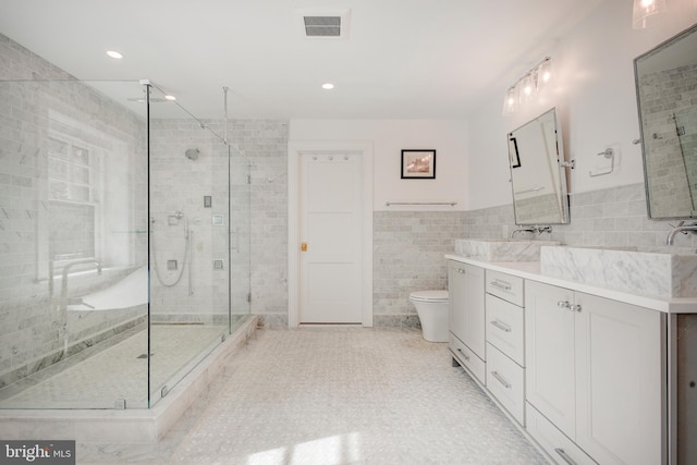 bathroom with vanity, tile walls, tile flooring, toilet, and a shower with shower door