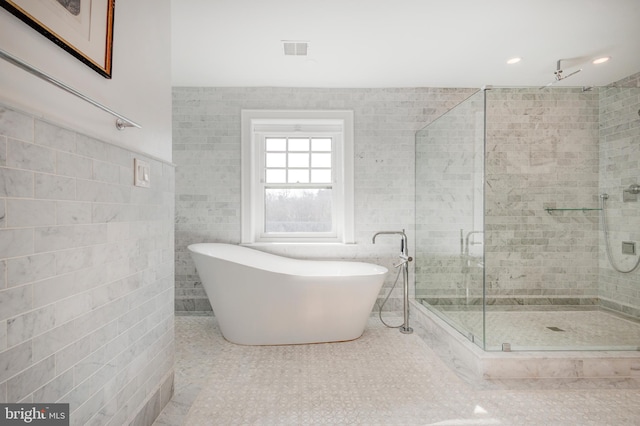 bathroom with independent shower and bath, tile floors, and tile walls