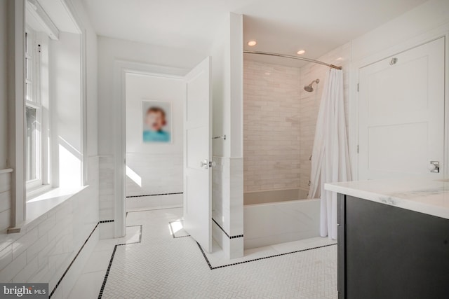 bathroom with tile flooring, shower / bath combo with shower curtain, tile walls, and vanity